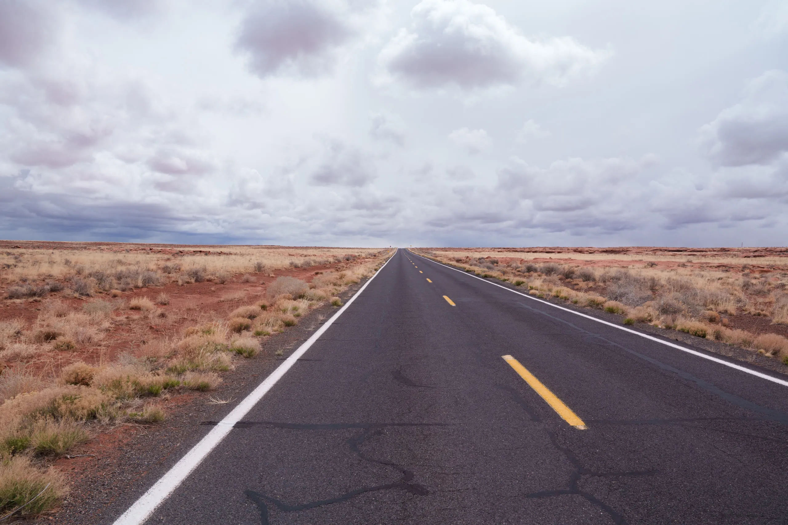 An empty desert highway running straight to the horizon